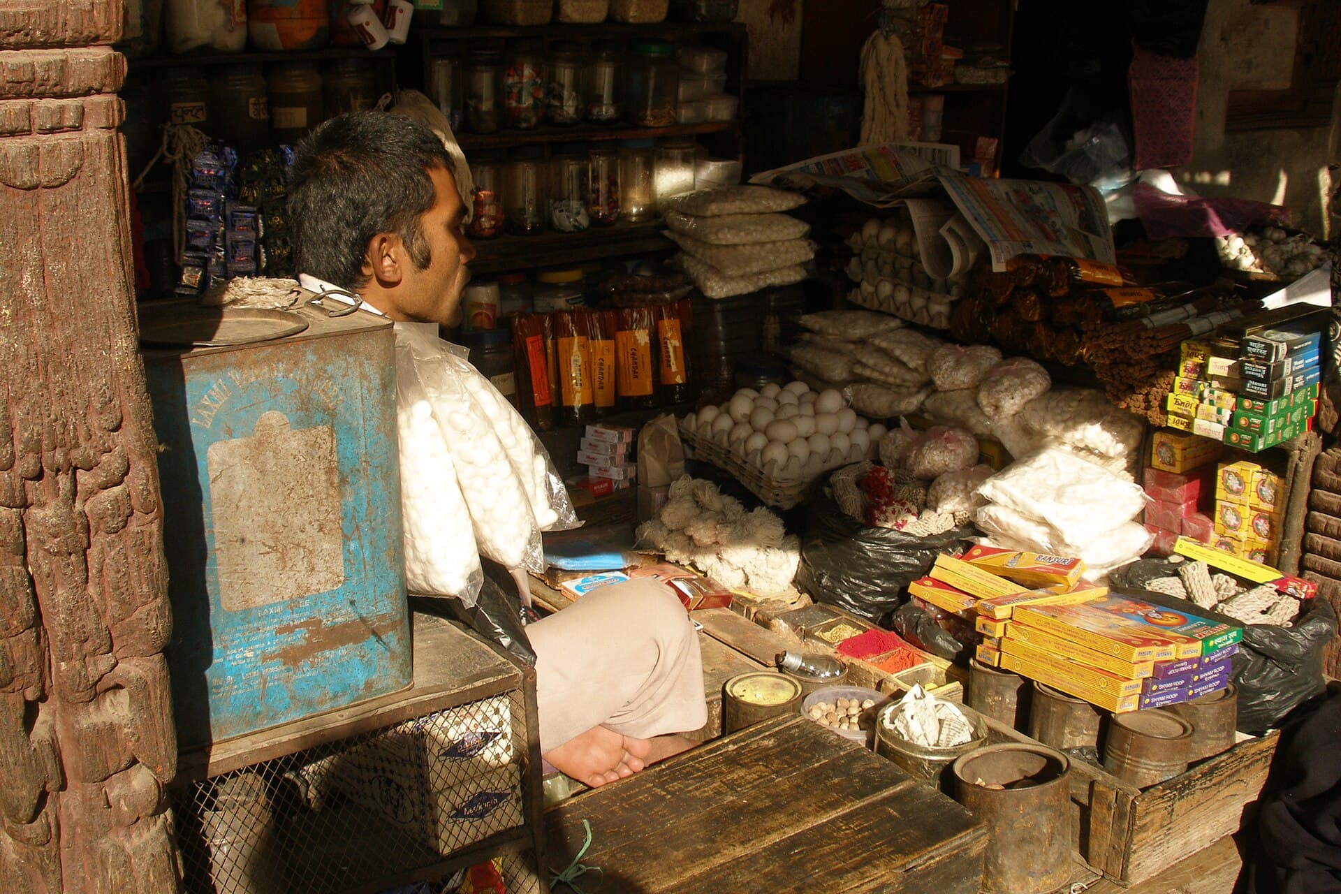 A shopkeeper at his counter in Basantapur, Kathmandu, surrounded by stock